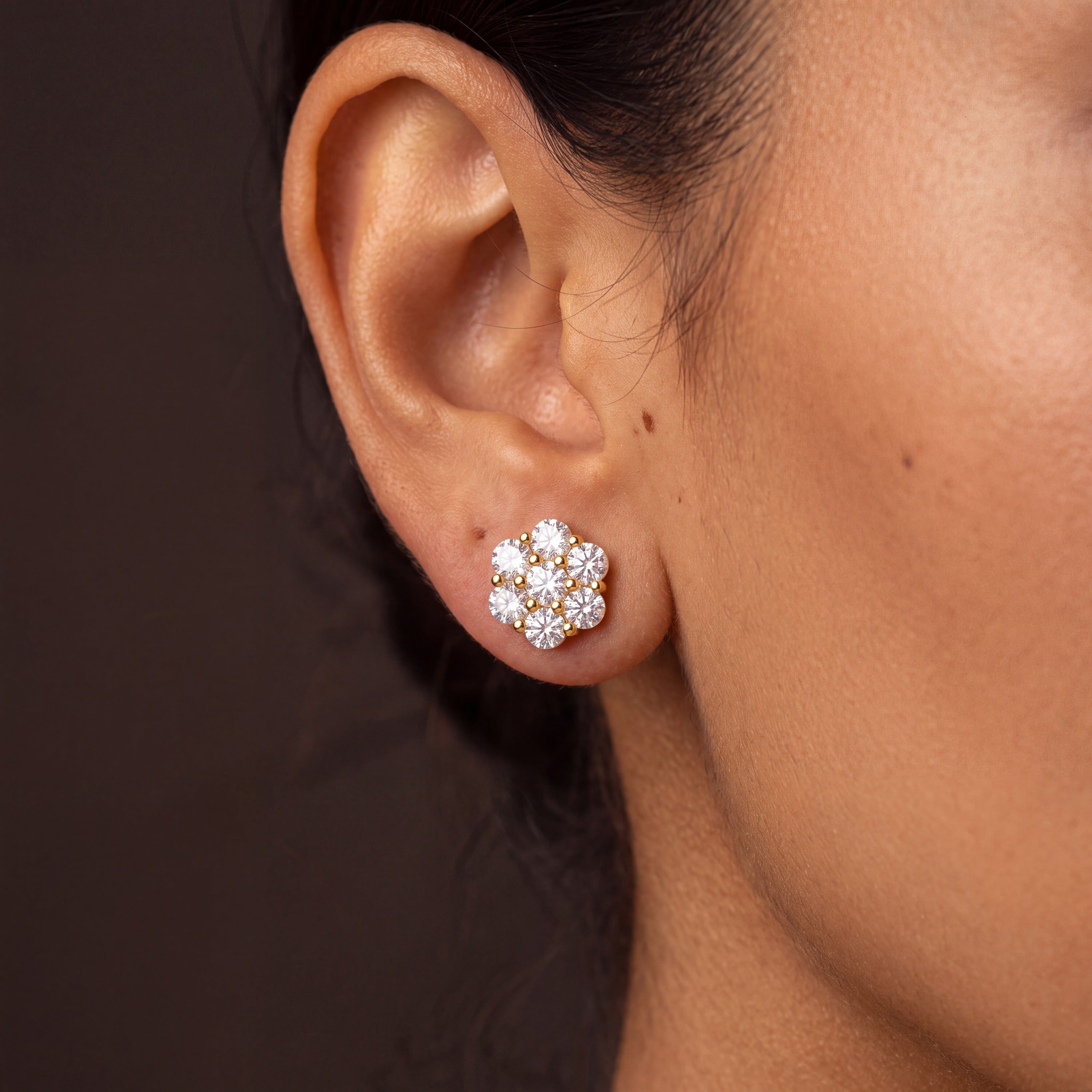Gold-plated moissanite flower cluster stud earring worn on an ear